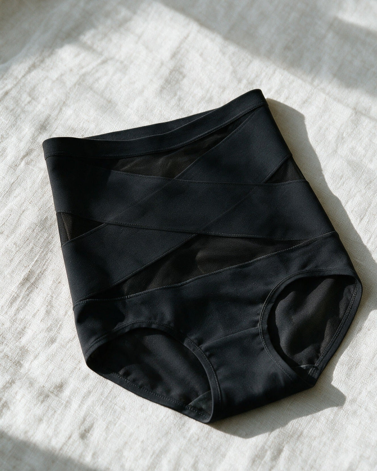 Haven Postpartum Support Brief in Black, laid on linen
